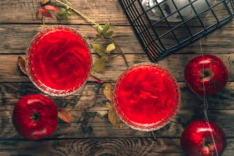 Red apple mocktail with shimmer on wooden rustic background