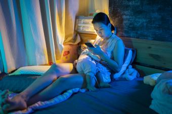 Woman feeding baby and watching phone 