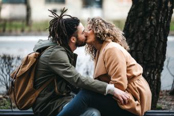 Young couple in love, sitting on a park bench and kissing