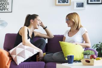 Two happy young women in the couch talking to each other