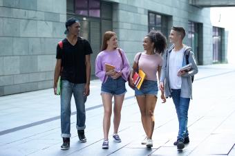 teenagers with books walking campus during lessons break