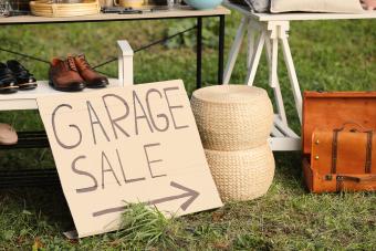 Sign Garage sale written on cardboard near tables