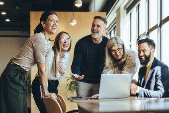 Happy businesspeople laughing while collaborating on a new project in an office