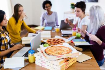 Group of young women at home studying and having pizza