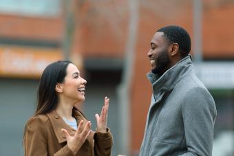 Side view portrait of a happy interracial relation with woman and man talking in the street