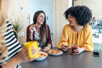 Shot of three smart entrepreneur women talking while taking a break and having a breakfast in the kitchen at coworking place.